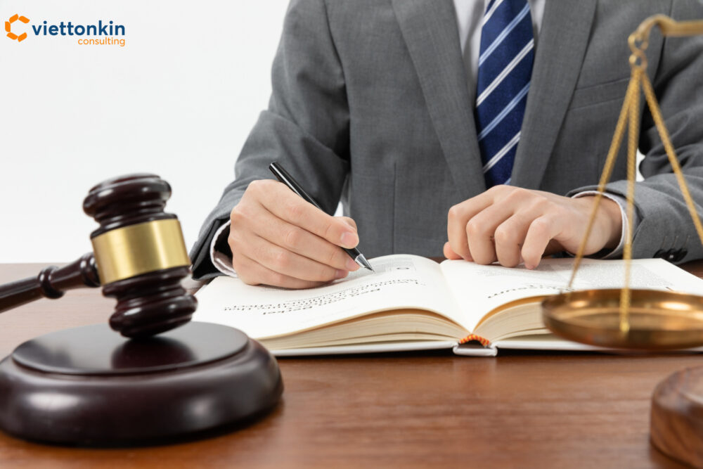 A lawyer in a suit writing in a legal book with a gavel and scales on the desk, symbolizing Vietnam’s legal safeguards, intellectual property protection, and regulatory modernization